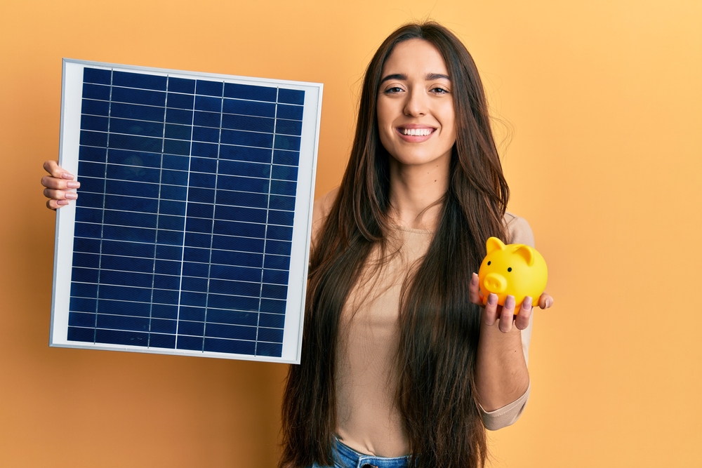 Young,Hispanic,Girl,Holding,Photovoltaic,Solar,Panel,And,Piggy,Bank